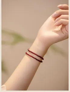 Detailed macro view of a delicate 3mm deep red garnet beaded bracelet on a slender wrist.