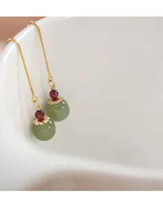 Detail of natural Hetian jade earrings with 14k gold threader design and red beads.