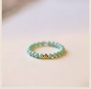 Macro view of a delicate 2mm turquoise bead ring featuring a single 14k gold accent bead.