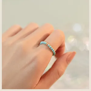 Close-up detail of a 2mm turquoise bead ring with a single gold accent worn on a finger.