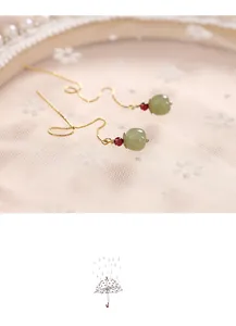 Close-up of elegant long 14k gold ear threads with natural green Hetian jade beads