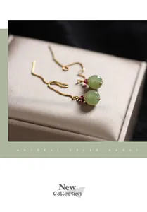 Close-up of elegant 14k gold line earrings with natural green jade beads on a jewelry box.
