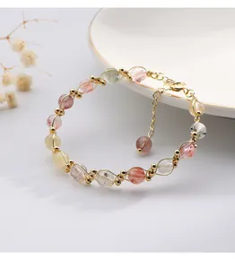Detailed view of handmade woven gold wire bracelet with colorful rutilated quartz beads.