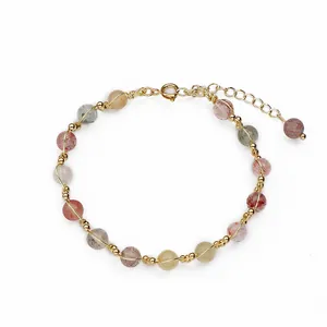 Natural multi-color rutilated quartz crystal bracelet with gold-tone wire wrapping on white