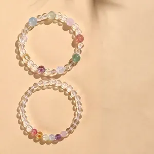 Elegantes Perlenarmband aus weißem Kristall und verschiedenen Edelsteinen auf Beige