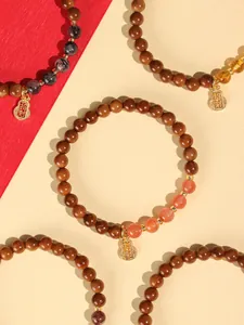 Detail von Holzperlenarmbändern mit Steinakzenten und goldenem Glücksbringer-Anhänger