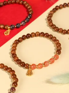 Detailansicht von Naturholz-Perlenarmband mit Karneol und goldenem Kürbis-Anhänger.