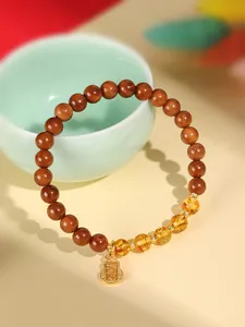 Handgefertigtes Kuku-Nuss-Armband mit Bernsteinperlen und Goldanhänger für Damen.