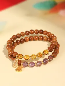 Nahaufnahme von Naturholzperlenarmbändern mit lila und bernsteinfarbenen Kristallen