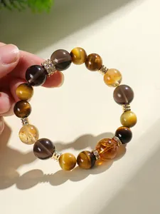 Vue macro d'un bracelet en œil de tigre et quartz fumé avec des touches dorées.