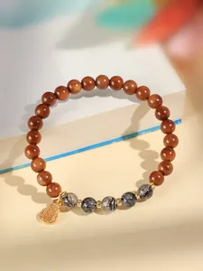 Makro-Detail des Kuka-Samen-Armbands mit Kristallperlen und goldenem Flaschenkürbis.