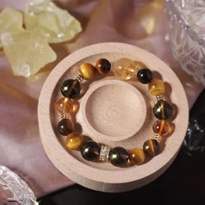 Bracelet en œil de tigre naturel et cristal jaune sur un support de présentation en bois.