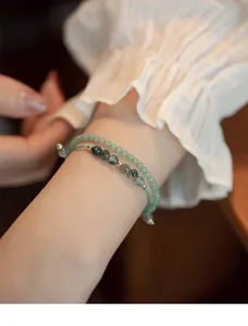 Primer plano de pulsera de capas de ágata musgosa y piedra verde con manga rizada.