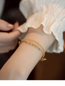 Close-up of delicate citrine and rutilated quartz bracelets on a woman's wrist.