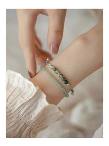 Primer plano detallado de pulseras de ágata musgosa y piedra verde superpuestas en la muñeca