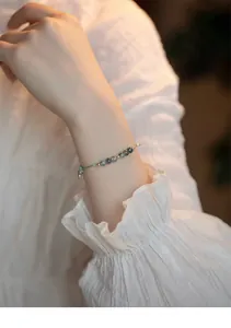 Vista detallada de una delicada pulsera de ágata con pequeñas cuentas de oro en una muñeca