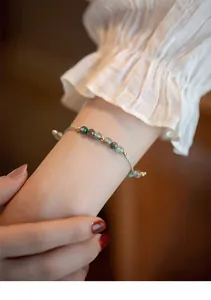 Primer plano de una delicada pulsera de ágata musgosa y cuentas de oro de 14k en una muñeca