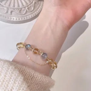 Detailopname van een kristallen armband met citrien, maansteen en 14k gouden ketting.