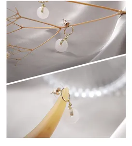 Gros plan détaillé de boucles d'oreilles en jade blanc avec fil doré sur fond de satin soyeux