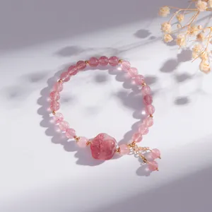 Detail van natuurlijke aardbeienkwarts armband met kattenpoot bedeltje en kwastjes
