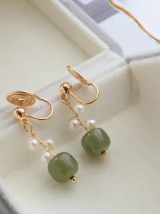 Détail macro de boucles d'oreilles clip en jade vert naturel et perles dorées