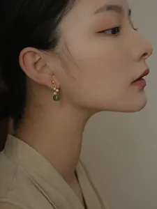 Détail en gros plan de boucles d'oreilles en jade vert et perles portées par un modèle