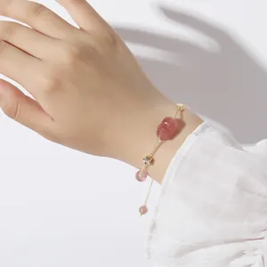 Detailopname van een natuurlijke aardbeikristallen armband met gouden sterbedeltjes