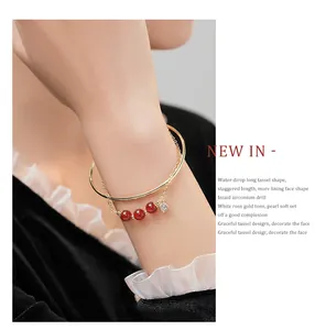 Gedetailleerde close-up van gouden armband met rode carneool kralen en een hartbedeltje