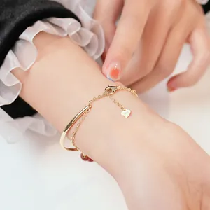 Elegant gouden armbandje met hartbedeltje en rode agaatkralen om een vrouwenpols