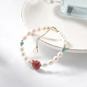 Elegant freshwater pearl bracelet with cinnabar owl and turquoise accents on white plate