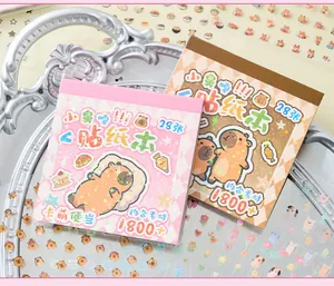 Detail showing two cute capybara cartoon sticker books on a silver tray
