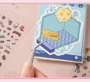 Detailaufnahme einer Pinzette, die einen Aufkleber auf das DIY-Miniaturbuch klebt