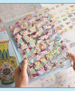 Close-up view of vintage Chinese porcelain shard stickers inside a DIY scrapbook