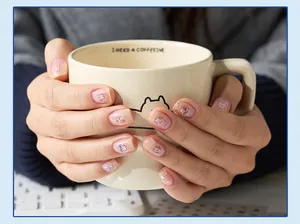 Macro view of cute animal PET stickers applied to fingernails holding a cream mug