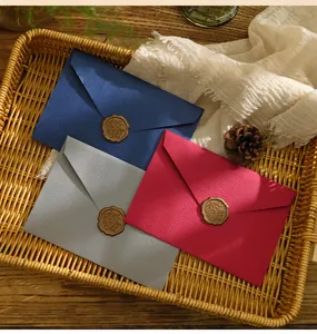 Vista dettagliata di buste vintage in blu, grigio e rosso con carta strutturata e sigillo di cera.