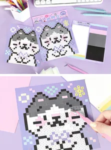 Close-up of DIY pixel art sticker kit showing tweezers applying square stickers to a cat design