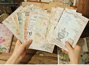 Assorted vintage decorative material paper sheets held in hand for scrapbooking journal decor.