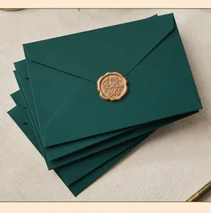 Close-up of dark green envelopes with elegant golden "For You" wax seal on fabric.