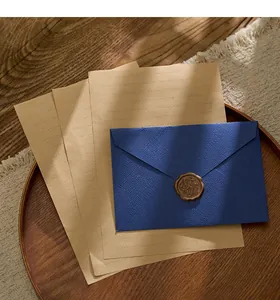 Primer plano de sobre azul marino con textura tejida, sello de lacre y papel kraft