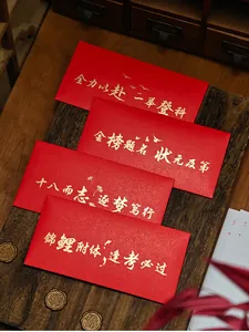 Close-up of four red envelopes with gold Chinese calligraphy on a wooden board.