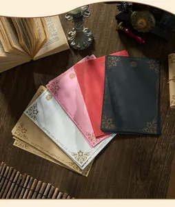 Fogli di carta da lettere vintage assortiti con motivi di rose su tavolo in legno scuro.