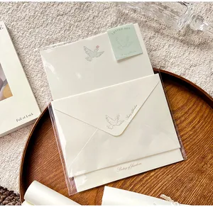 Detail view of a cream letter set with dove motifs in clear packaging on a wooden tray