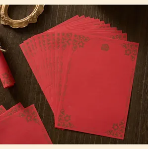 Primo piano di carta da lettere rossa vintage con eleganti motivi floreali dorati