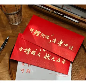 Close-up of red graduation envelopes with gold calligraphy lettering on wood tray