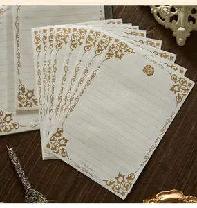 Vista dettagliata della carta da lettere vintage con eleganti rose dorate e motivi a vite.