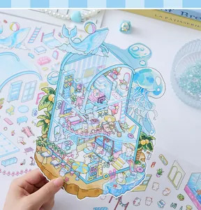 Macro view of a colorful 3D miniature beach house PET sticker held by hand for journal collage