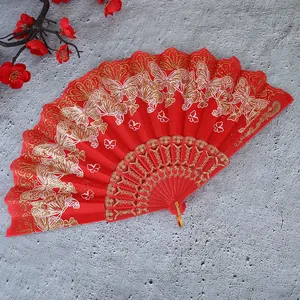 Vista detallada de un abanico chino rojo con elegantes patrones de mariposas doradas