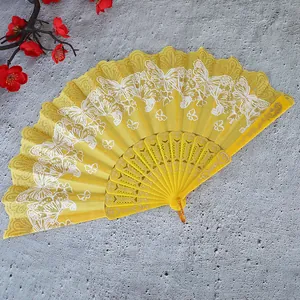 Detalle del intrincato patrón de mariposa blanca en un abanico plegable chino amarillo
