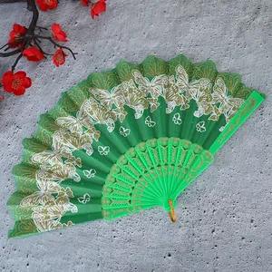 Detalle de un abanico plegable chino verde con patrones de mariposas y purpurina dorada