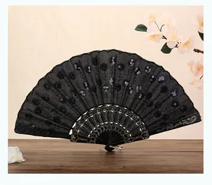 Elegante abanico plegable negro con bordado y lentejuelas sobre mesa de madera